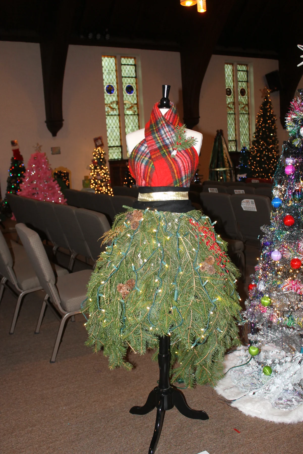 A dress-form Christmas tree with a plaid top and a skirt made of lit greenery