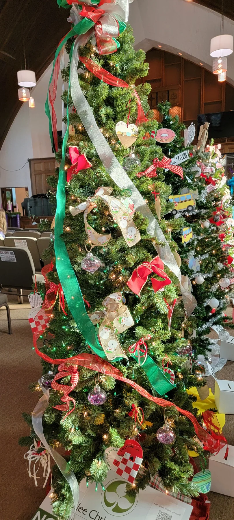 A Christmas tree wrapped with long red, green, and silver ribbons